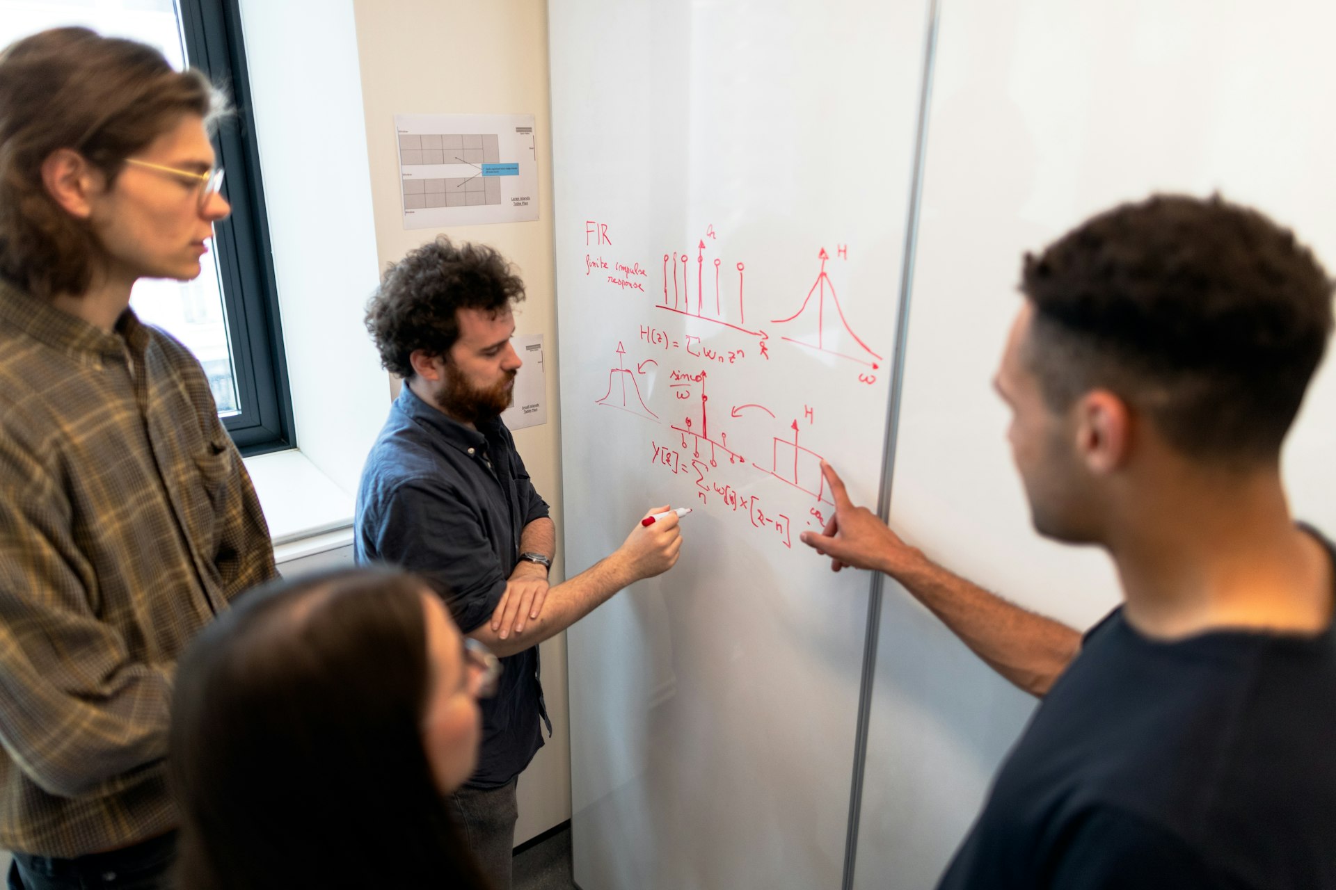 man in black crew neck t-shirt writing on white board